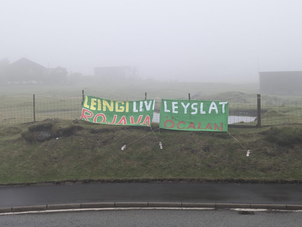 TWO banners hanging in a roundabout with the Faroese messages: "Leingi livi Rojava" and "Leyslat Öcalan"